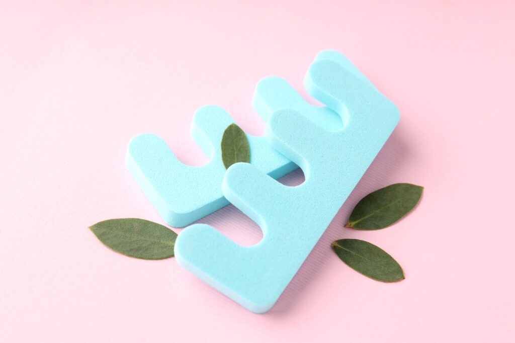 Nail separators and leaves on pink background